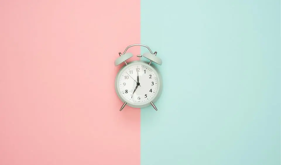 Photo of an analog clock with a pink and green background