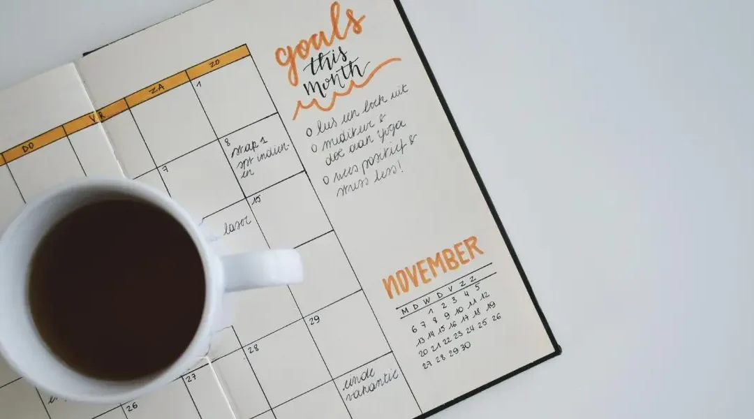 A calendar with a cup of coffee on top