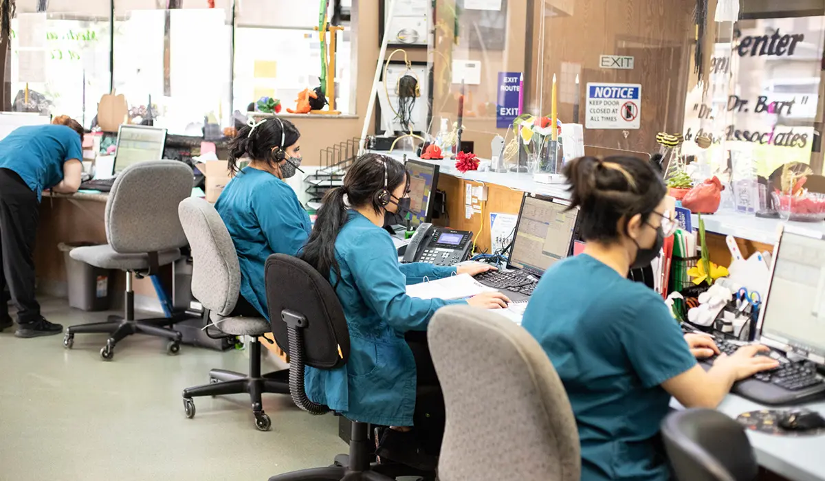 A group of Veterinary CSRs working hard at the front desk on computers