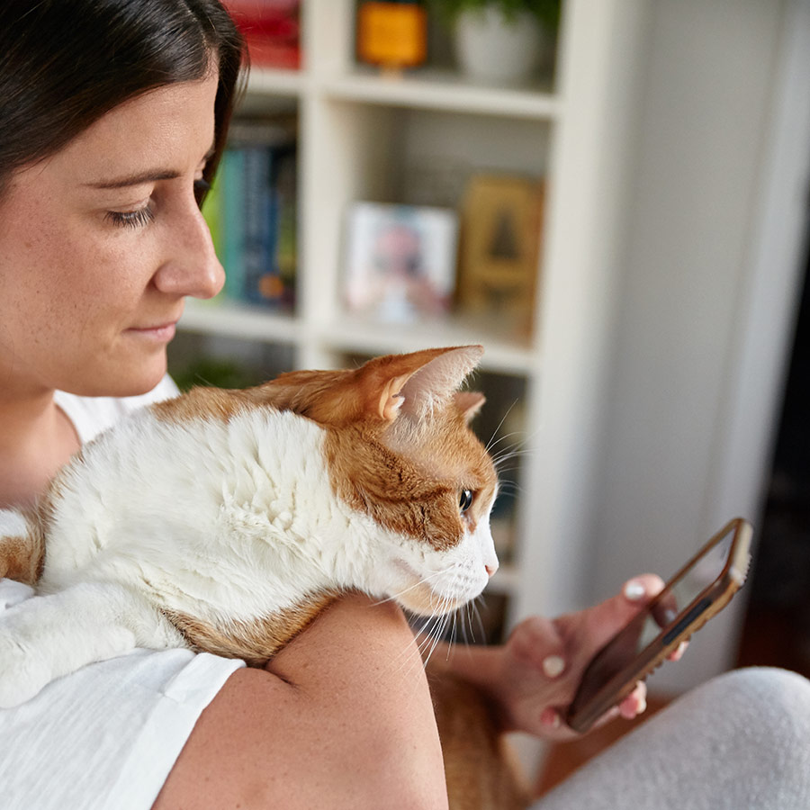 pet parent holding cat while using app