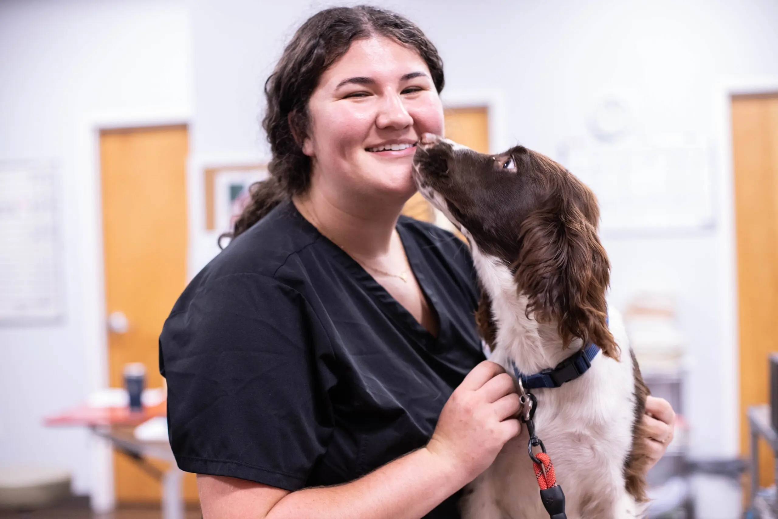 Smiling Vet Tech being licked by a dog