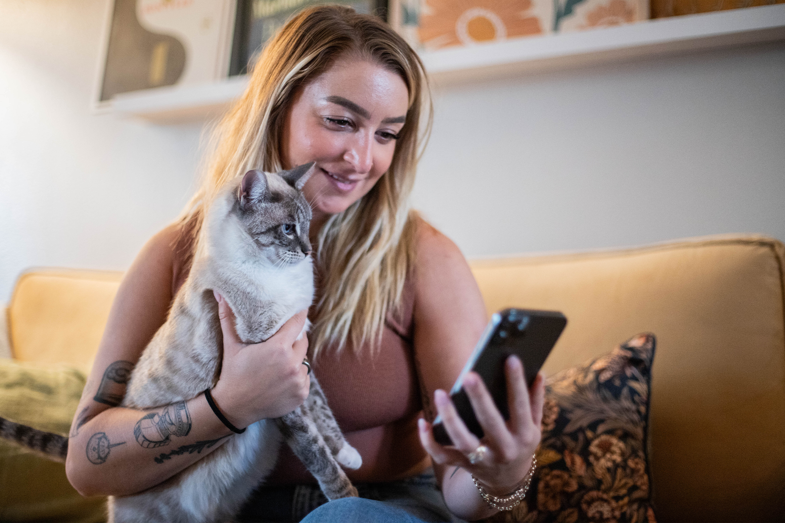 Pet parents holding their cat while using their phone